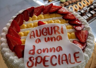 Deliziosa torta di compleanno decorata con fragole fresche e crema, con scritto "Auguri a una donna speciale", perfetta per celebrare occasioni speciali per le donne.