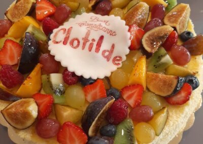 Succake con frutta fresca e crema, decorato con una varietà di frutta di stagione colorata e invitante, ideale per ricorrenze speciali e dessert raffinati.