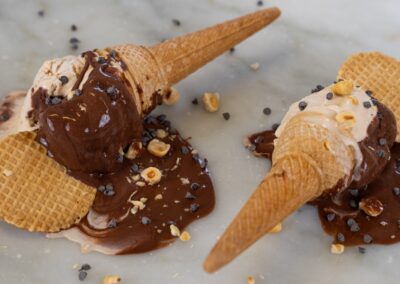 Croccanti coni di waffle glassati al cioccolato, decorati con nocciole tritate e chicchi di cioccolato, perfetti come dolce goloso o merenda irresistibile.