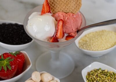 Gelato artigianale alla frutta con fragole, gusti cremosi, biscotti e decorazioni, presentato in coppa elegante con ingredienti di alta qualità. Perfetto per momenti di dolcezza e relax.