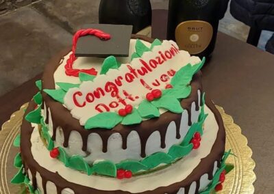 Dolce Pensier, torta di Natale decorata con cioccolato, foglie verdi e bacche rosse, perfetta per celebrazioni festive e occasioni speciali.