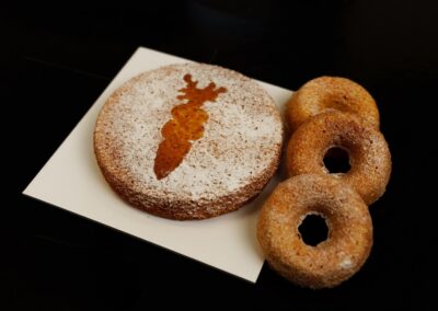 Delizie di pasticceria con dolci decorati, tra cui un biscotto decorato con forma di cervo e ciambelle con zucchero, perfetti per occasioni speciali e momenti di dolcezza artigianale.