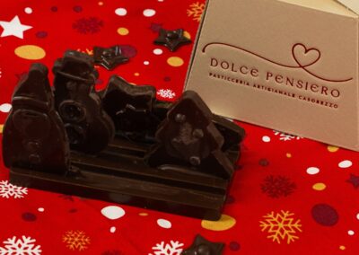 Delizie di cioccolato e regalo natalizio di Dolce Pensiero, su sfondo natalizio ricco di stelle e fiocchi di neve con confezione originale.